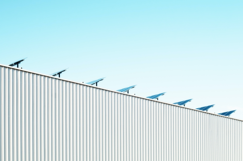 View of the side of a commercial warehouse with solar panels on the roof.